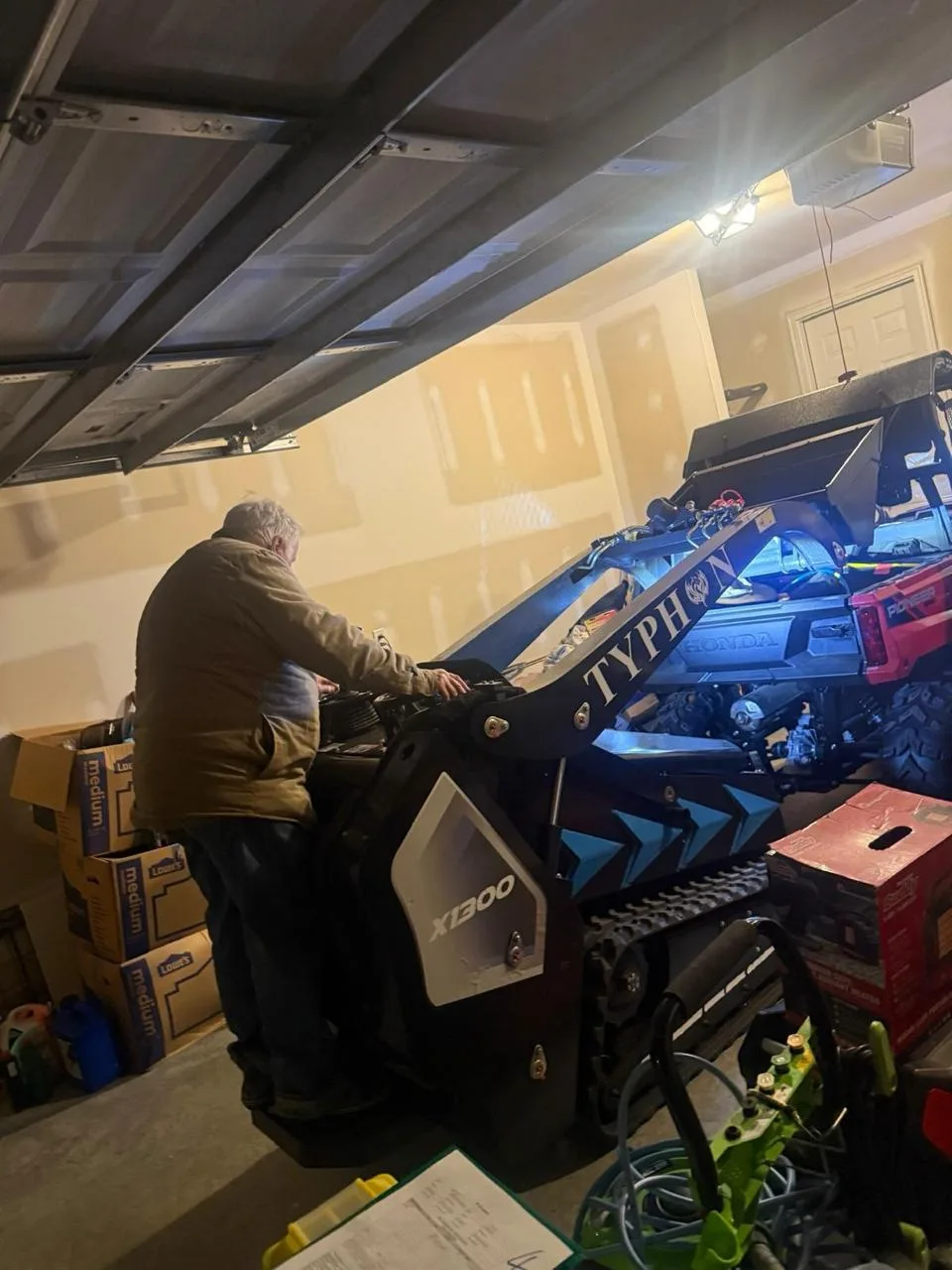 Technician servicing TYPHON mini skid steer in service workshop