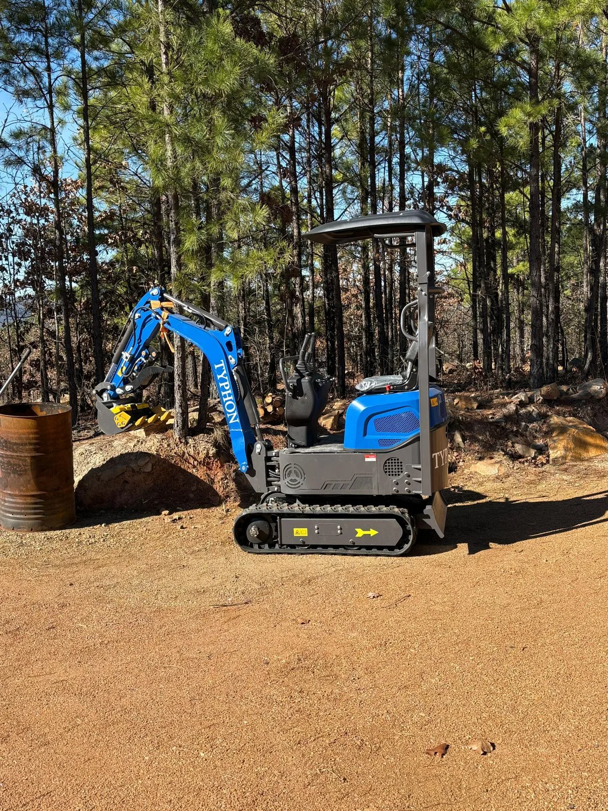 Blue compact mini excavator positioned for tree clearing and digging