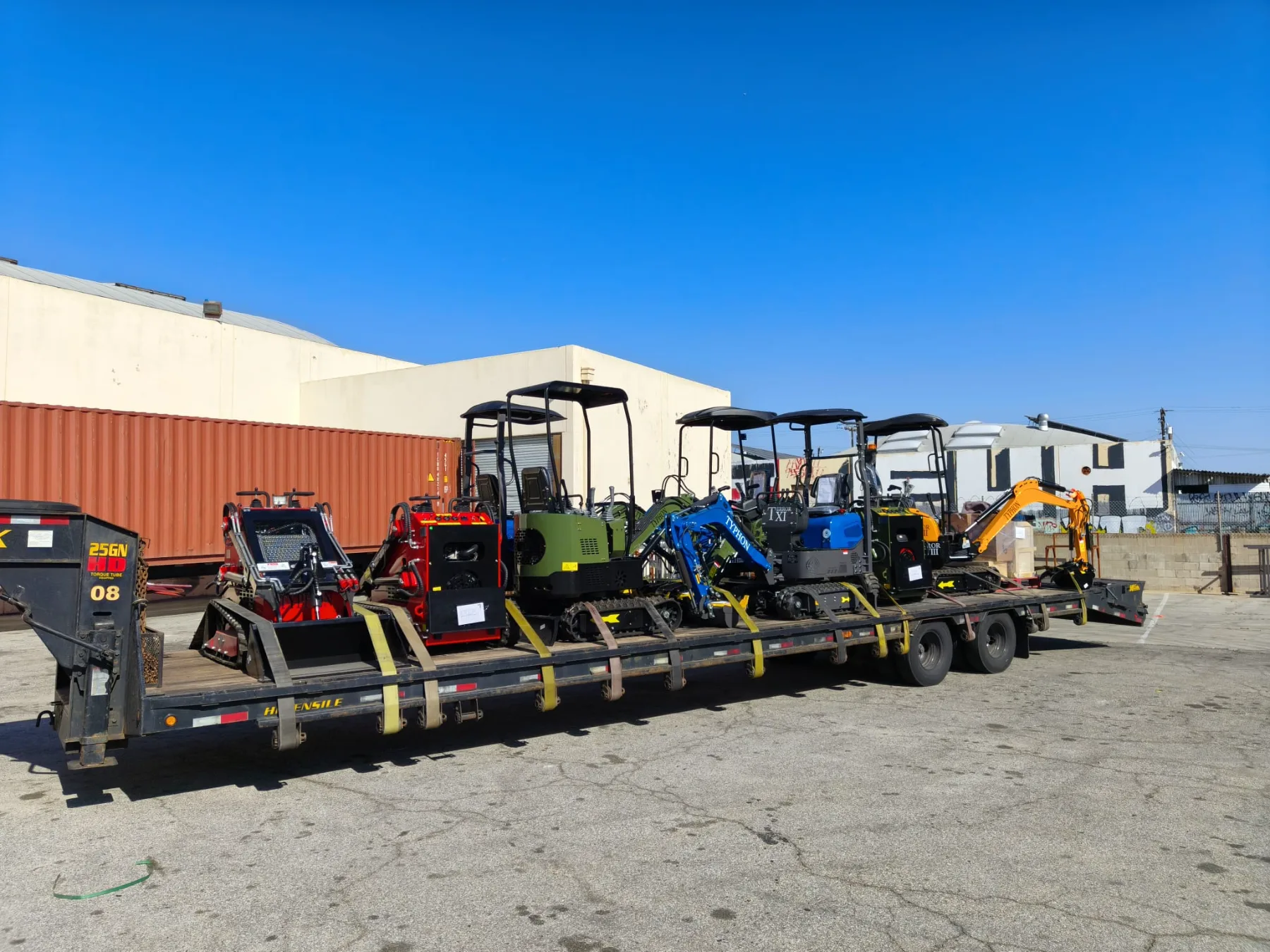 Compact excavators and skid steers loaded onto transport trailer
