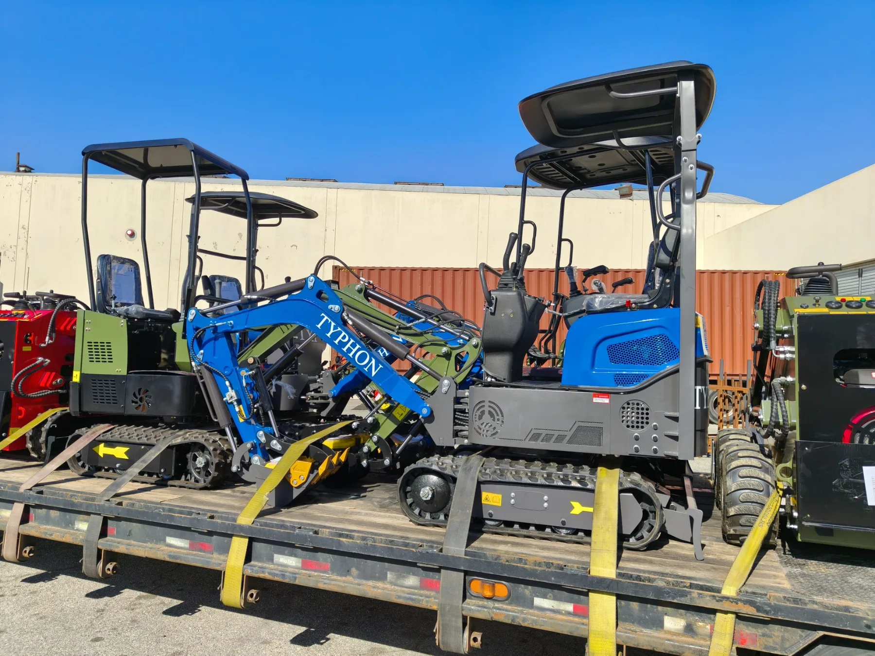 Lined up compact excavators and skid steers in facility lot